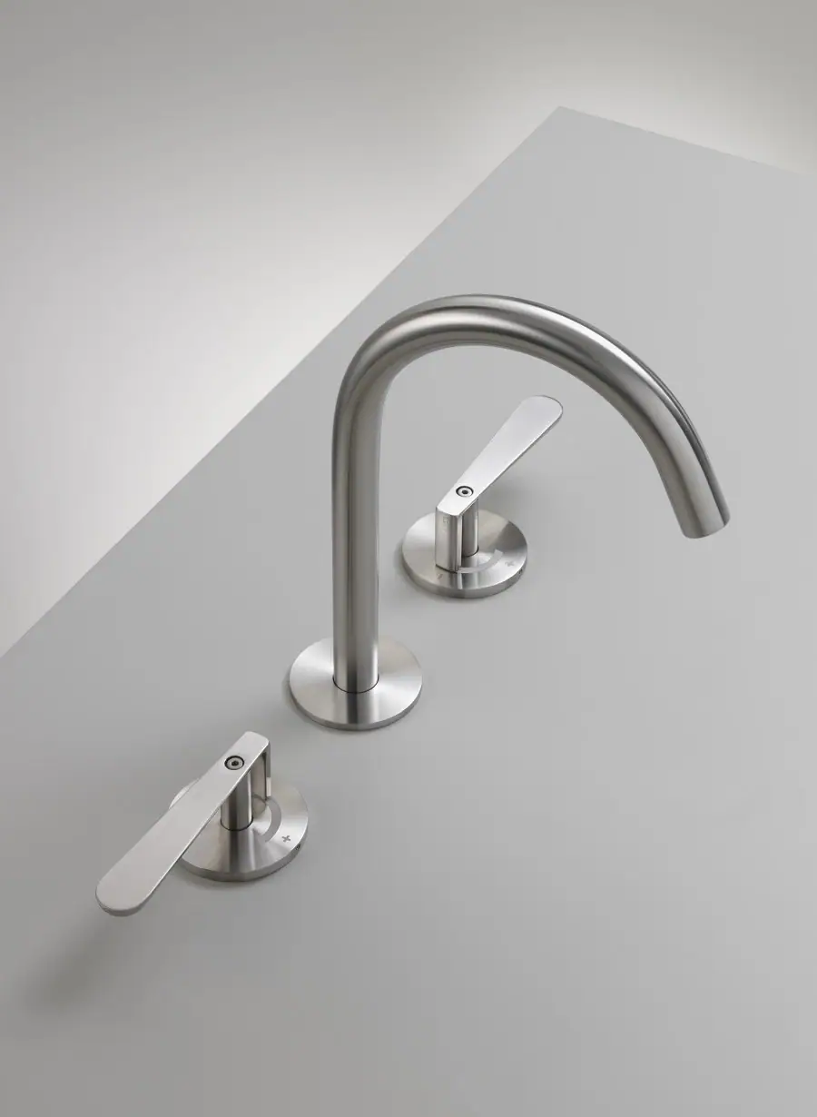 Grifo de lavabo de tres agujeros en acero satinado, con caño alto curvado y dos manetas sobre rosetones redondos
