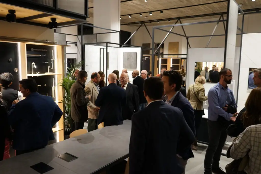 Grupo de invitados conversando entre los expositores de grifería y baño