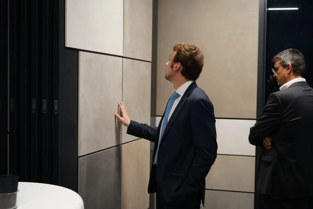 Dos invitados observan de cerca grandes placas de cerámica en un expositor