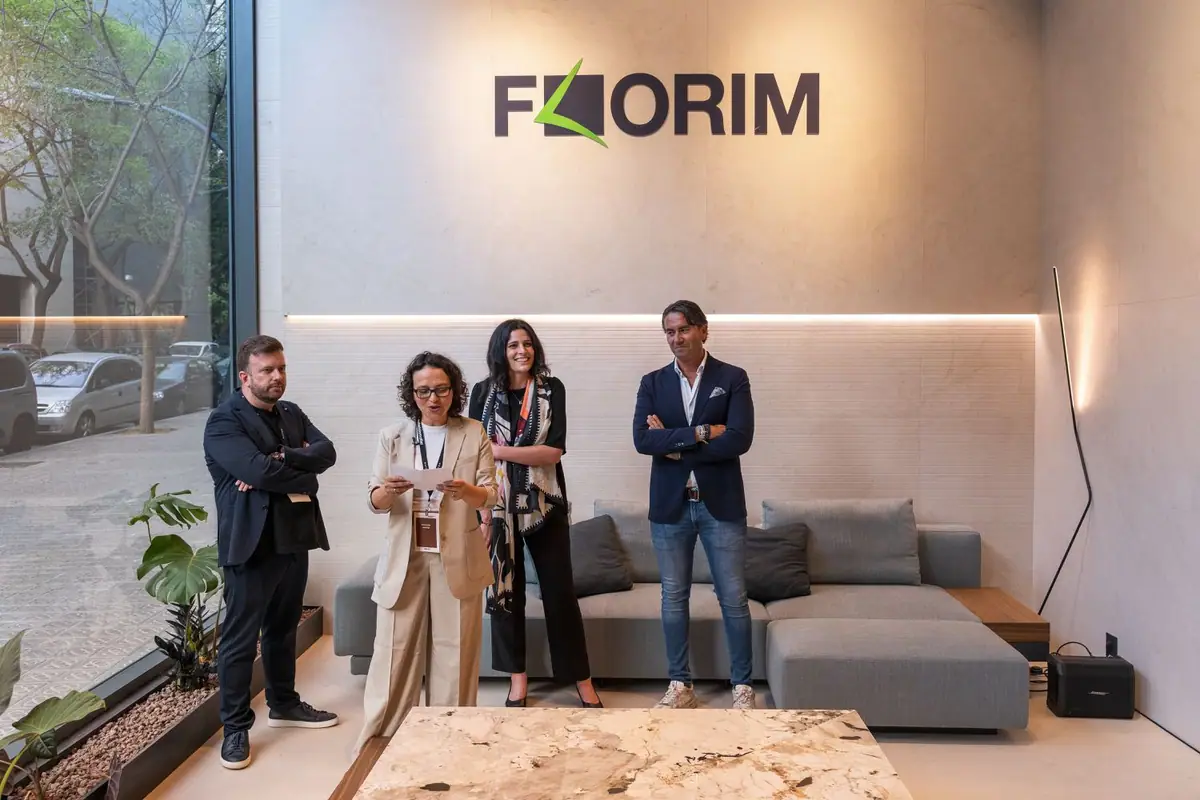 Cuatro personas presentan el espacio de pie bajo el logotipo de Florim, junto a un sofá y una mesa de piedra