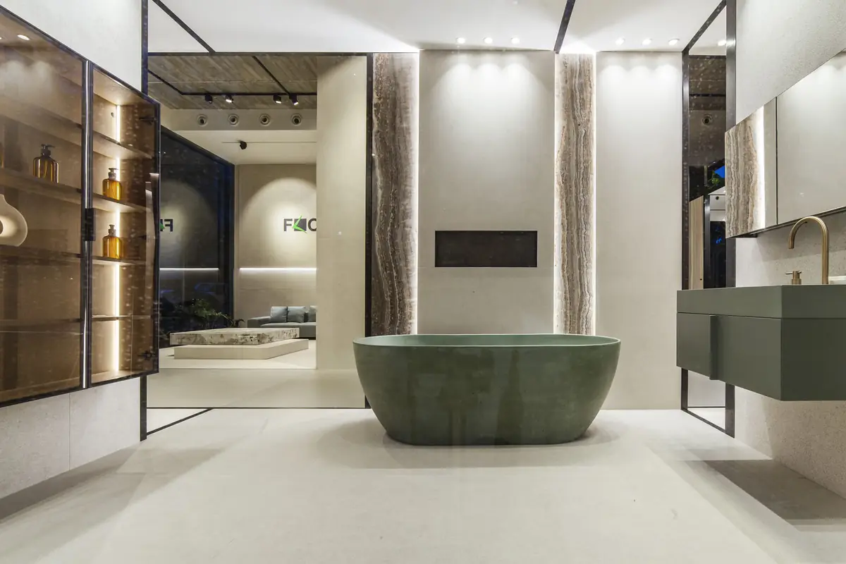 Baño con bañera exenta verde, lavabo suspendido y revestimientos de efecto piedra