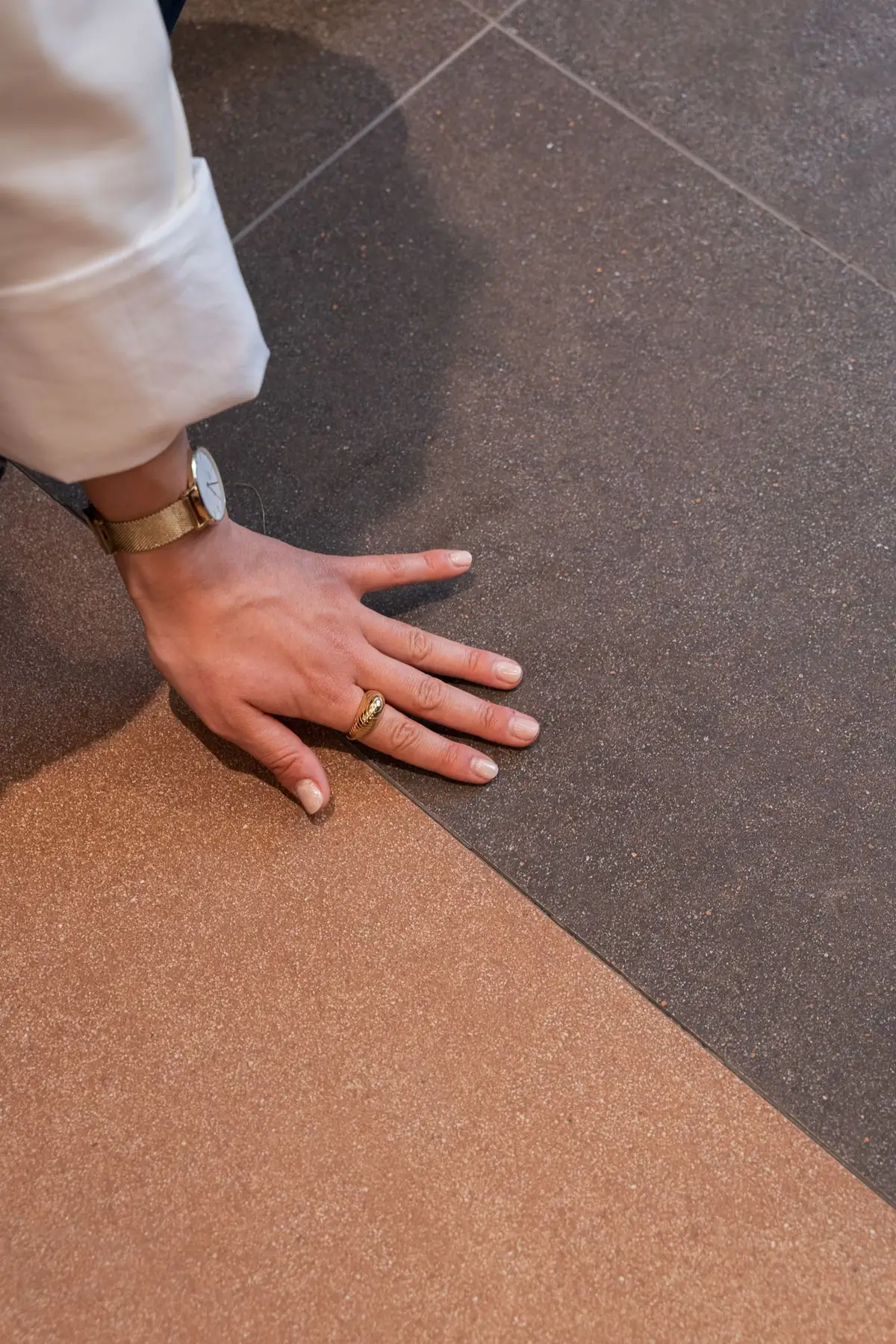 Mano apoyada sobre un pavimento cerámico de grano fino en dos tonos, marrón y terracota