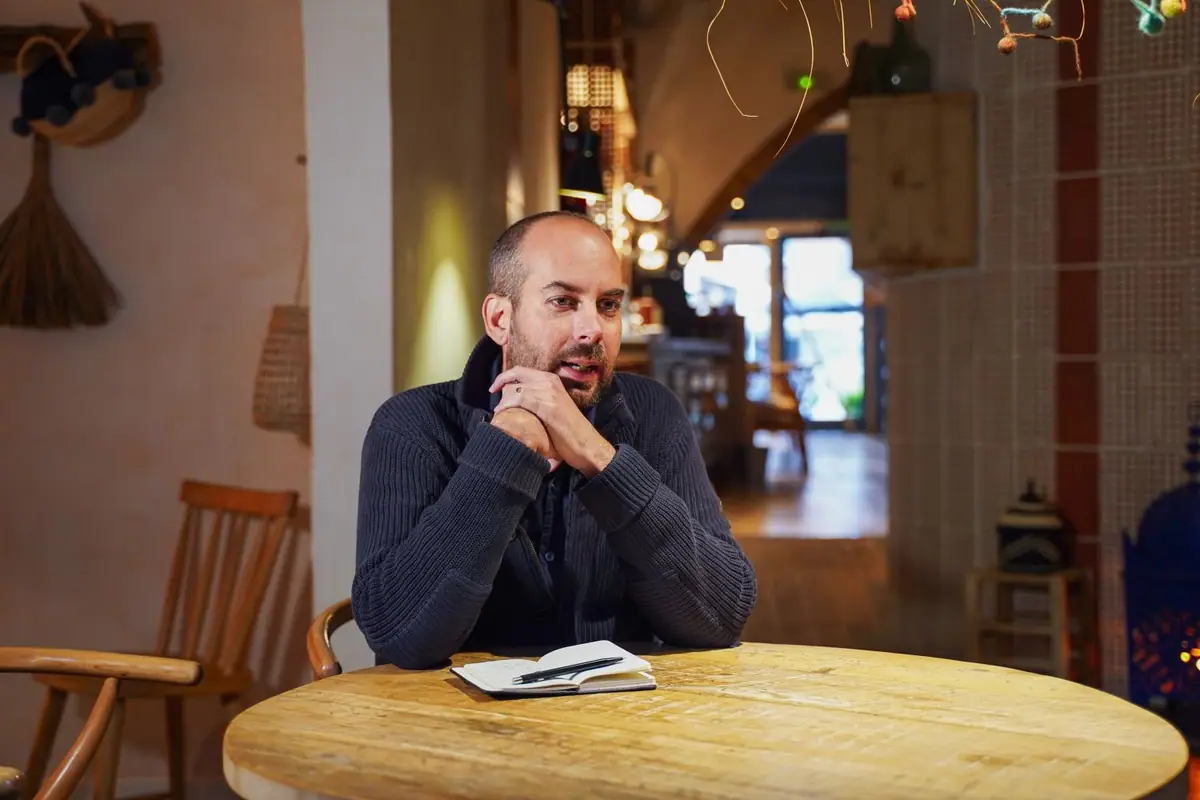 Una persona habla sentada a una mesa redonda de madera en el restaurante