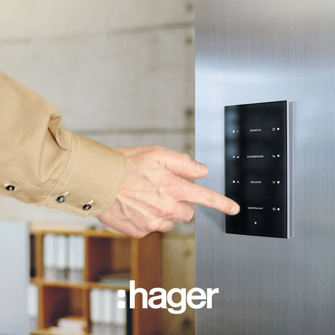 Dedo que pulsa un teclado táctil de cristal negro con funciones de luz, regulación y persianas en una pared de acero