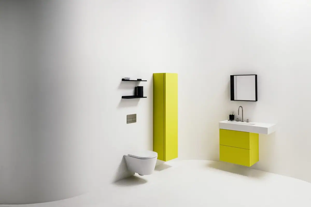 Baño con mueble de lavabo y columna lacados en amarillo, inodoro suspendido blanco y espejo y estantes negros
