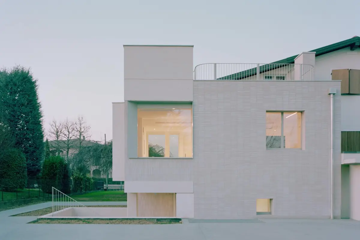 Vivienda unifamiliar con fachada revestida de piezas alargadas de piedra compactada blanca