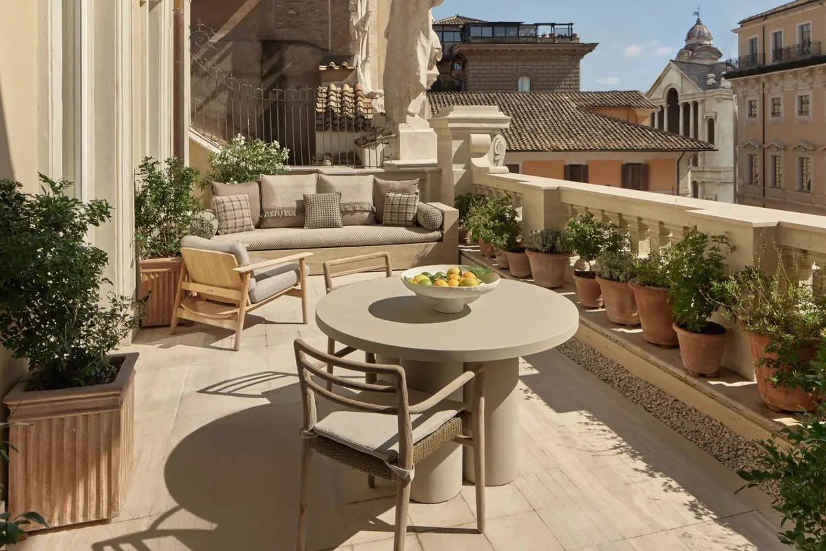 Terraza de una suite de hotel con vistas a los tejados de Roma y pavimento claro de piedra compactada