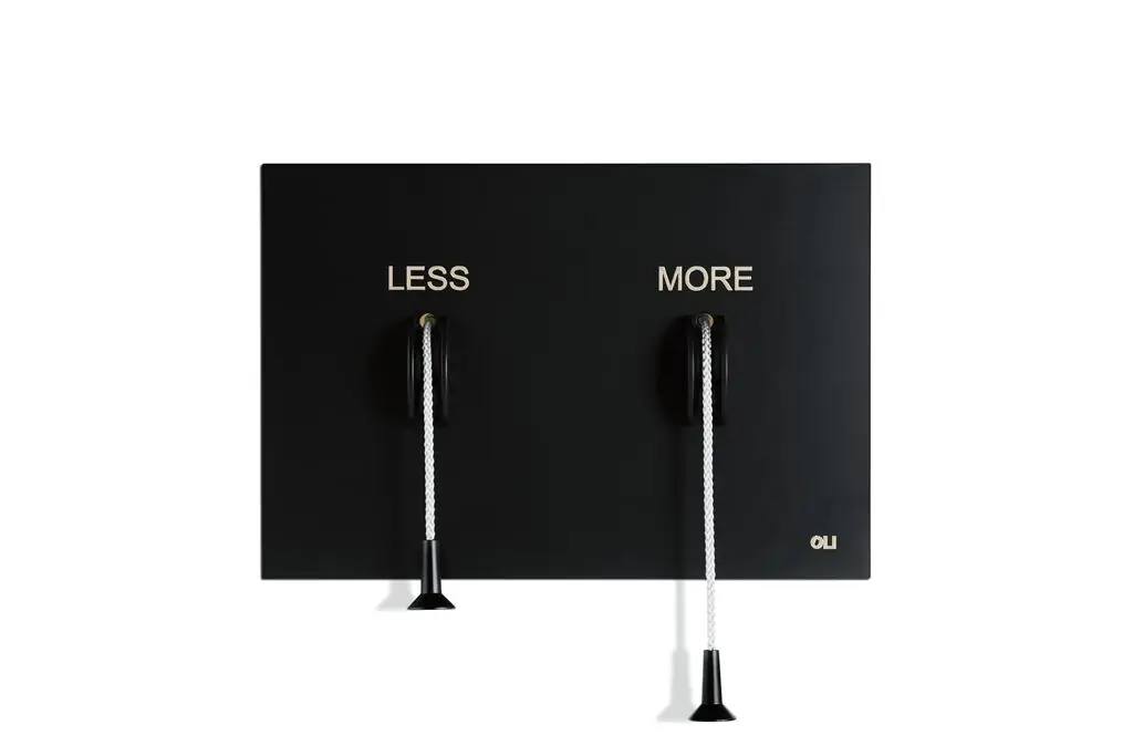 Placa negra rectangular con las palabras LESS y MORE y dos cordones blancos de distinta longitud rematados con tiradores negros