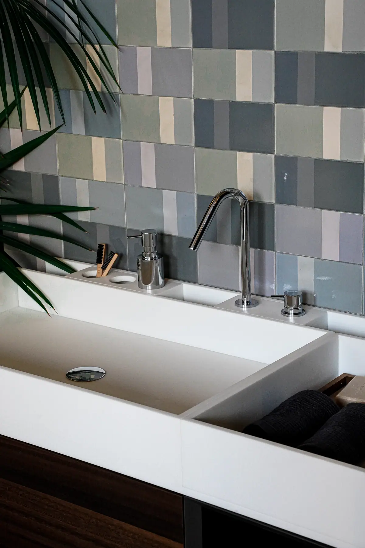 Detalle de un lavabo blanco con caño alto cromado, mando independiente y dosificador de jabón.