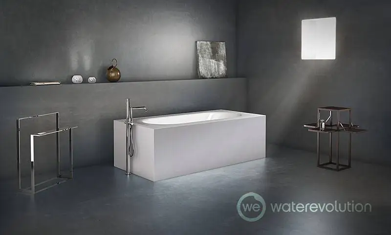 Bañera blanca con grifo de bañera de pie cromado, toallero y mesita metálicos en un baño de paredes grises.