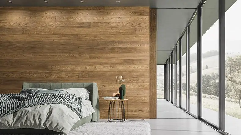Dormitorio con una pared revestida de tablas de madera en tono miel y ventanales hacia un paisaje de colinas