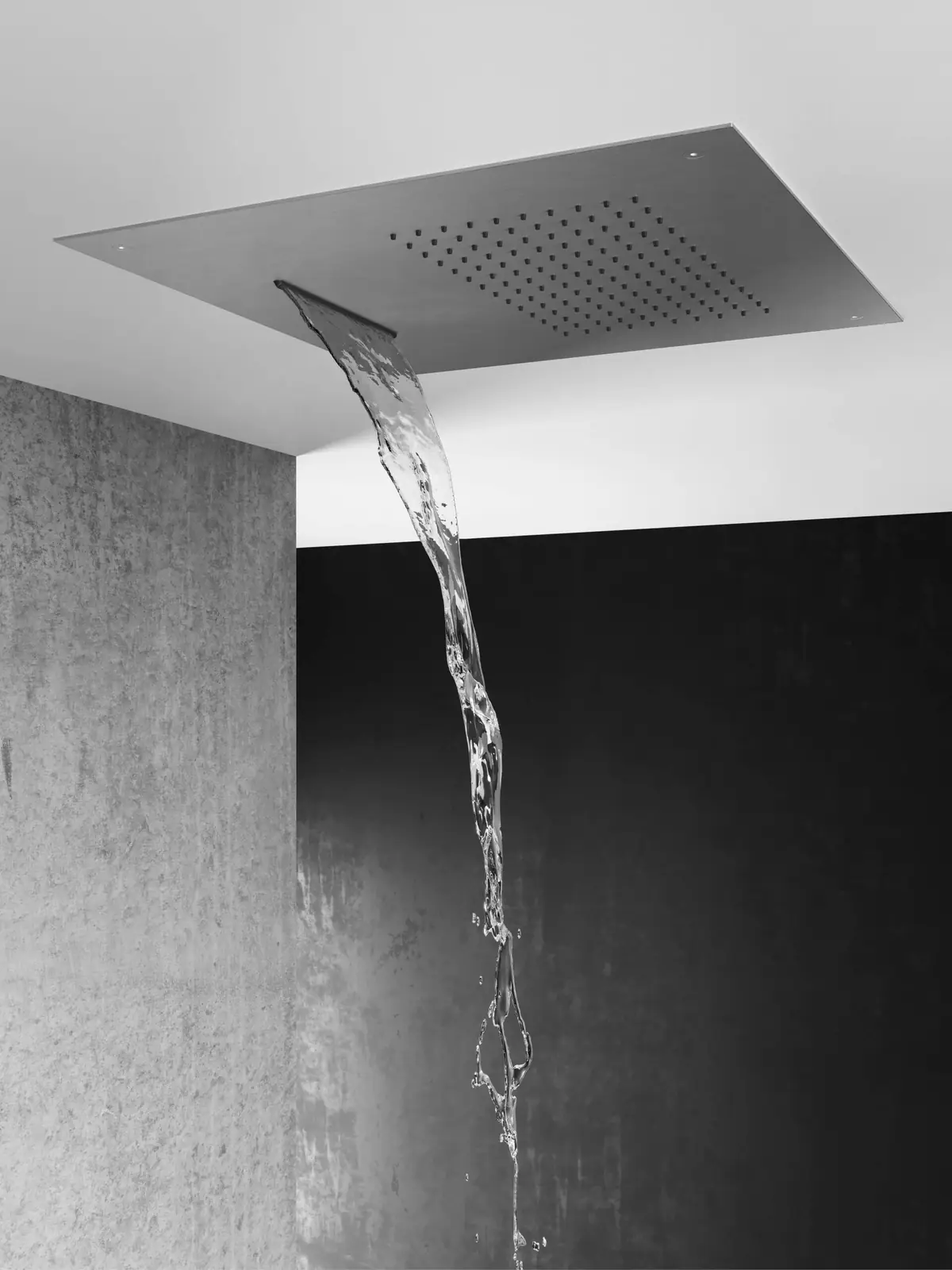Rociador de techo de acero del que cae una lámina de agua junto a una pared de hormigón