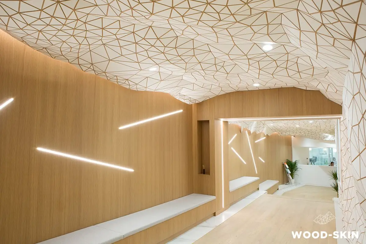 Pasillo con techo y pared revestidos de una malla teselada de triángulos blancos con juntas de madera, junto a paredes de madera con líneas de luz.