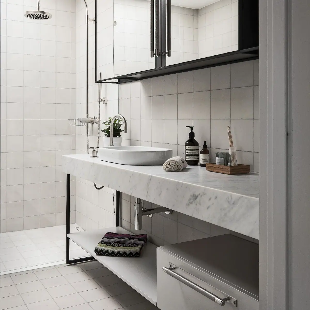 Baño con paredes de azulejo blanco, encimera de mármol con lavabo de apoyo y tirador de barra de acero en el cajón inferior