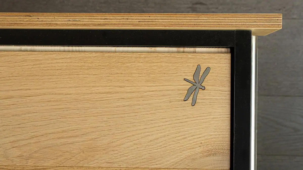Muestra de roble con una libélula metálica incrustada, símbolo de Mardegan Legno.