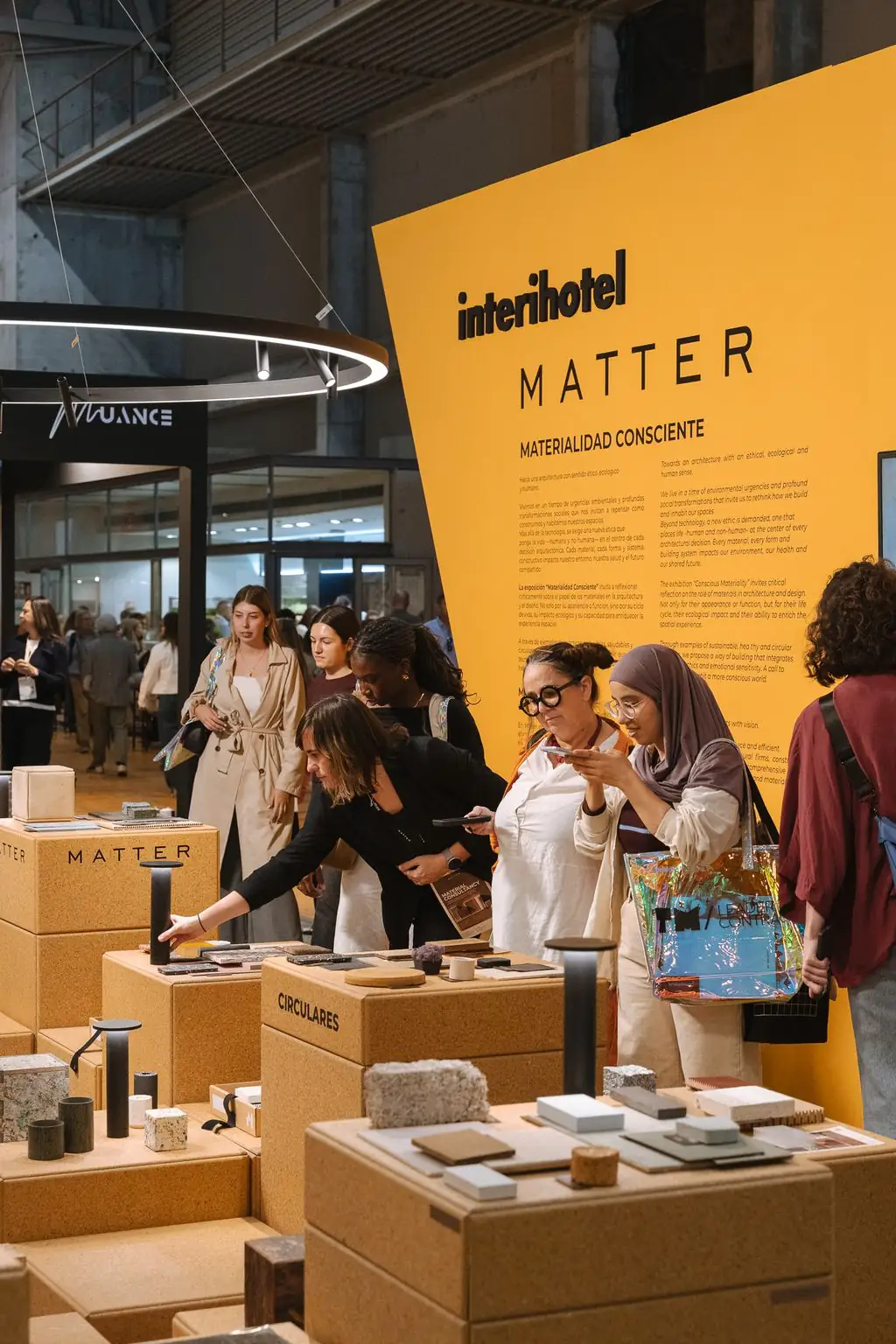 Grupo de visitantes manipulando muestras de materiales sobre las peanas