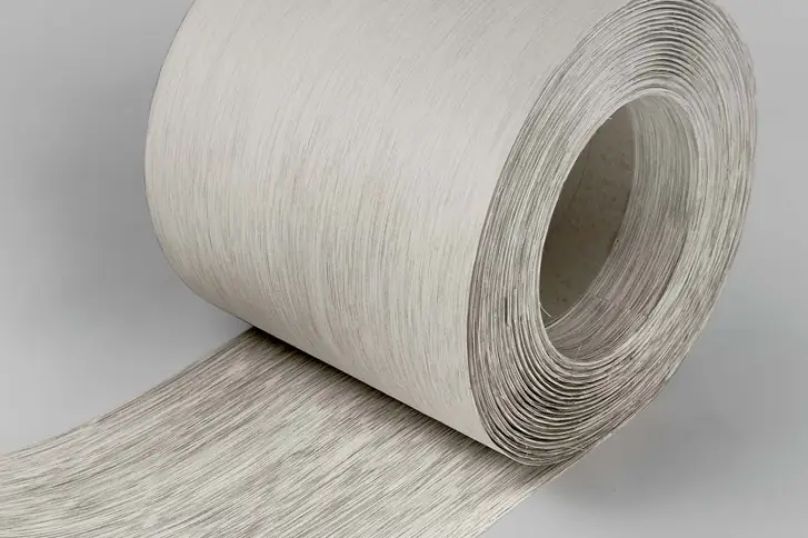 Rollo de chapa de ratán gris claro con veta lineal, parcialmente desenrollado.