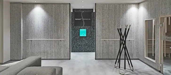 Zona de relax de un spa con paredes revestidas con paneles grises de veta lineal y un sofá en primer plano.