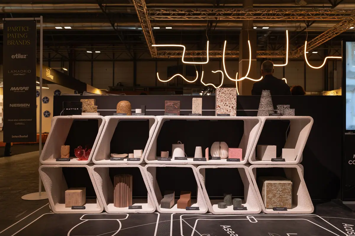 Estantería impresa en 3D con muestras de materiales y el panel de marcas participantes.