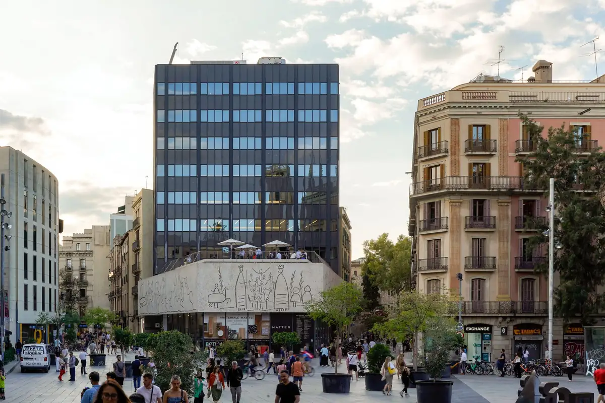 Fachada del edificio del COAC en la plaça Nova de Barcelona, con el friso esgrafiado de Picasso y la plaza llena de gente.