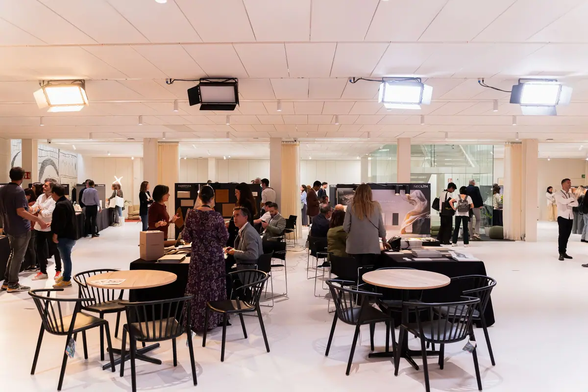 Zona de mesas y sillas entre los expositores de la primera planta, con visitantes conversando.