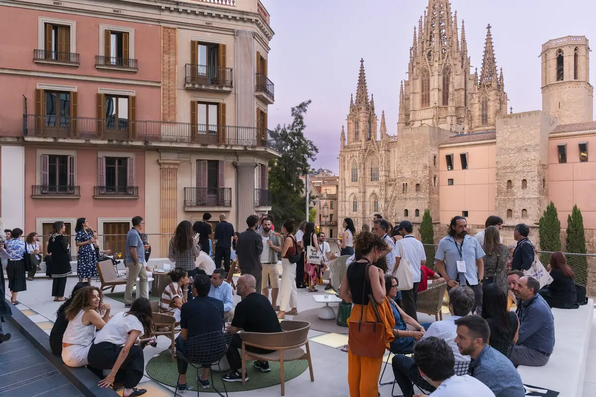 Asistentes reunidos en la terraza del COAC al atardecer, con la catedral de Barcelona al fondo.