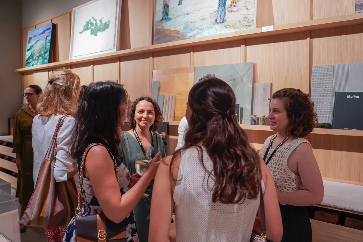 Invitadas conversando junto a las estanterías de muestras y la obra expuesta
