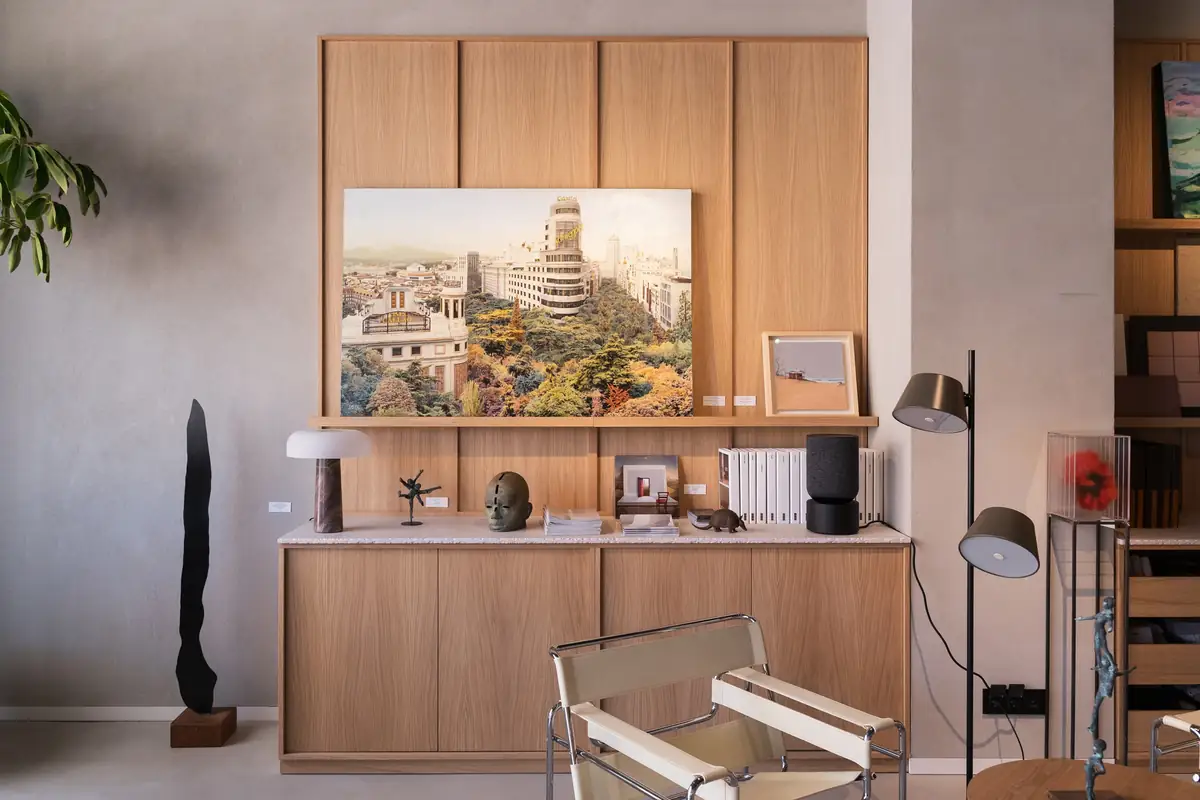 Mueble de madera con un cuadro urbano, una escultura y una butaca de cuero