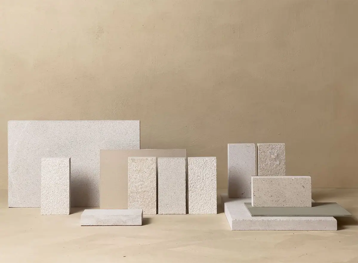 Piezas de piedra caliza clara de distintos tamaños y texturas sobre un fondo beige.