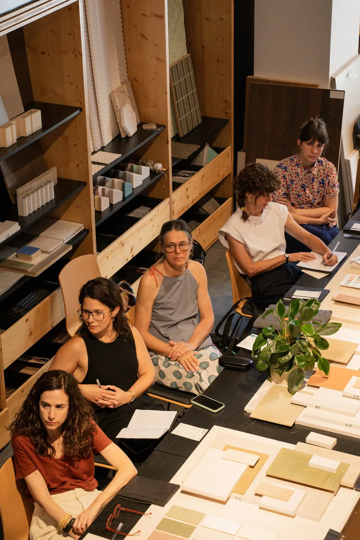 Arquitectas e interioristas escuchan la charla junto a las estanterías de muestras.