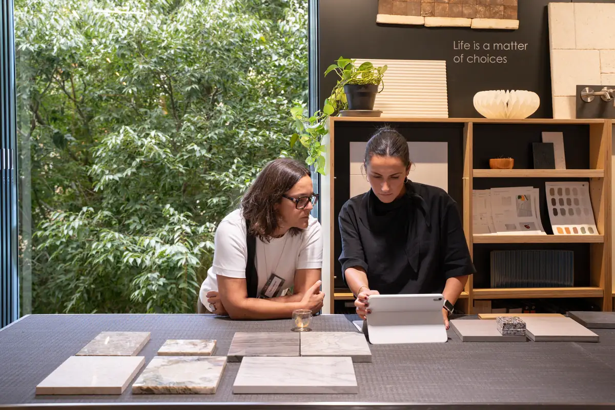 Dos mujeres consultan una tableta junto a muestras de mármol en la Materioteca de Matter Barcelona.