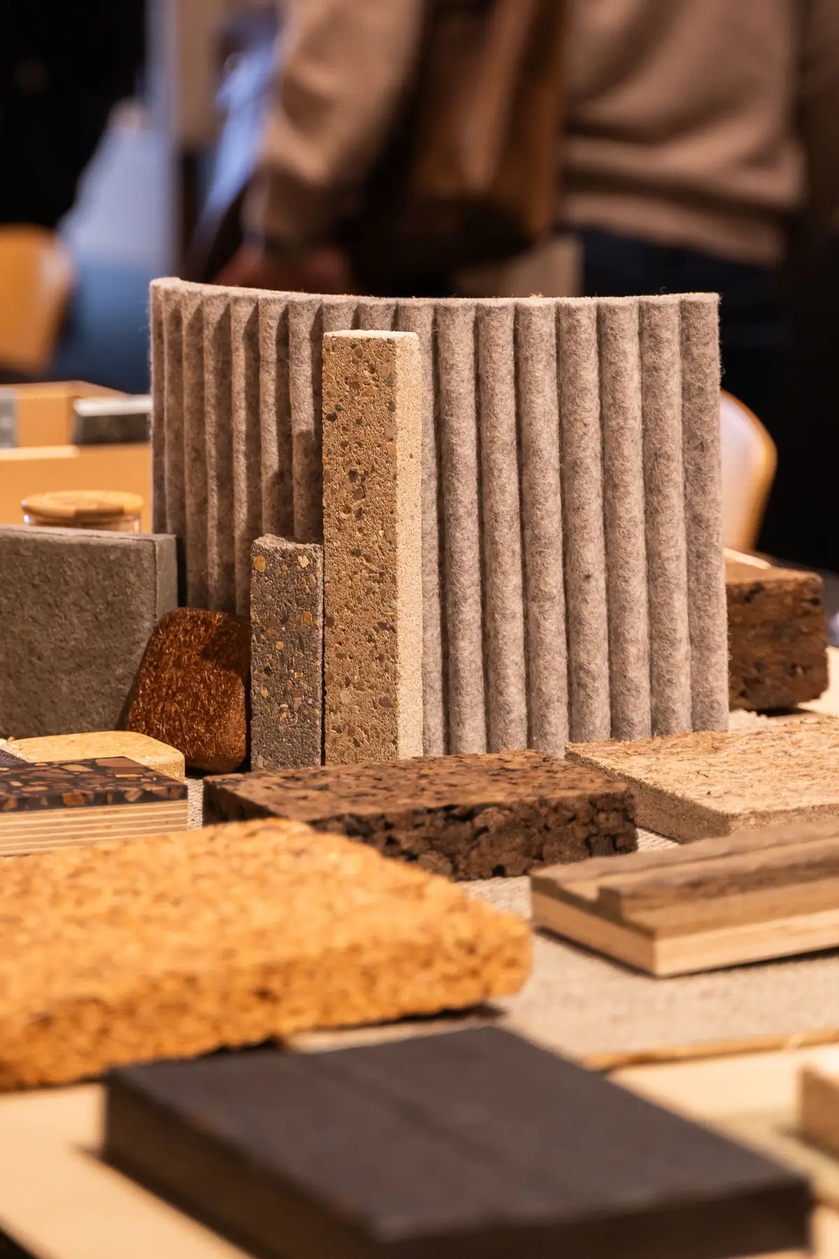 Muestras de corcho, aglomerados, madera y un panel ondulado de fieltro sobre la mesa.