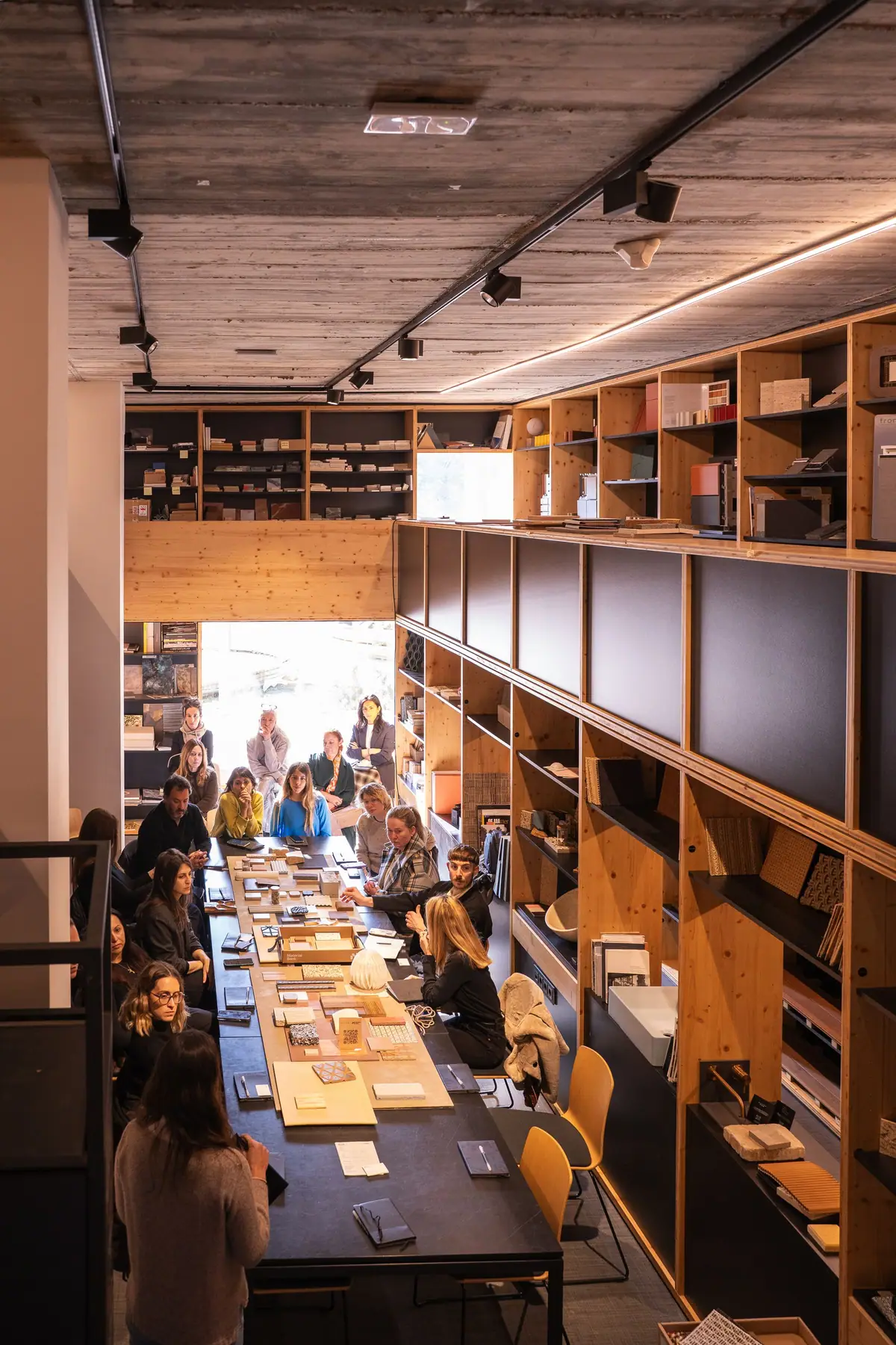 Vista de la materioteca con una larga mesa de muestras y los asistentes sentados a ambos lados, entre estanterías de madera.