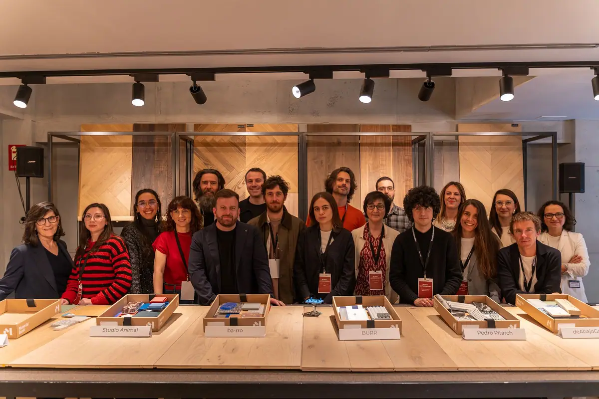 Grupo de arquitectos y equipos de Matter y Material Bank de pie tras una mesa con cajas de muestras de materiales