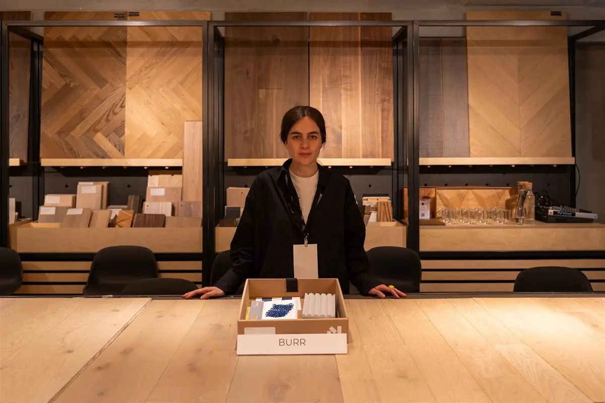 Elena Fuertes de pie tras la caja de muestras de BURR, con muestras textiles azules y blancas