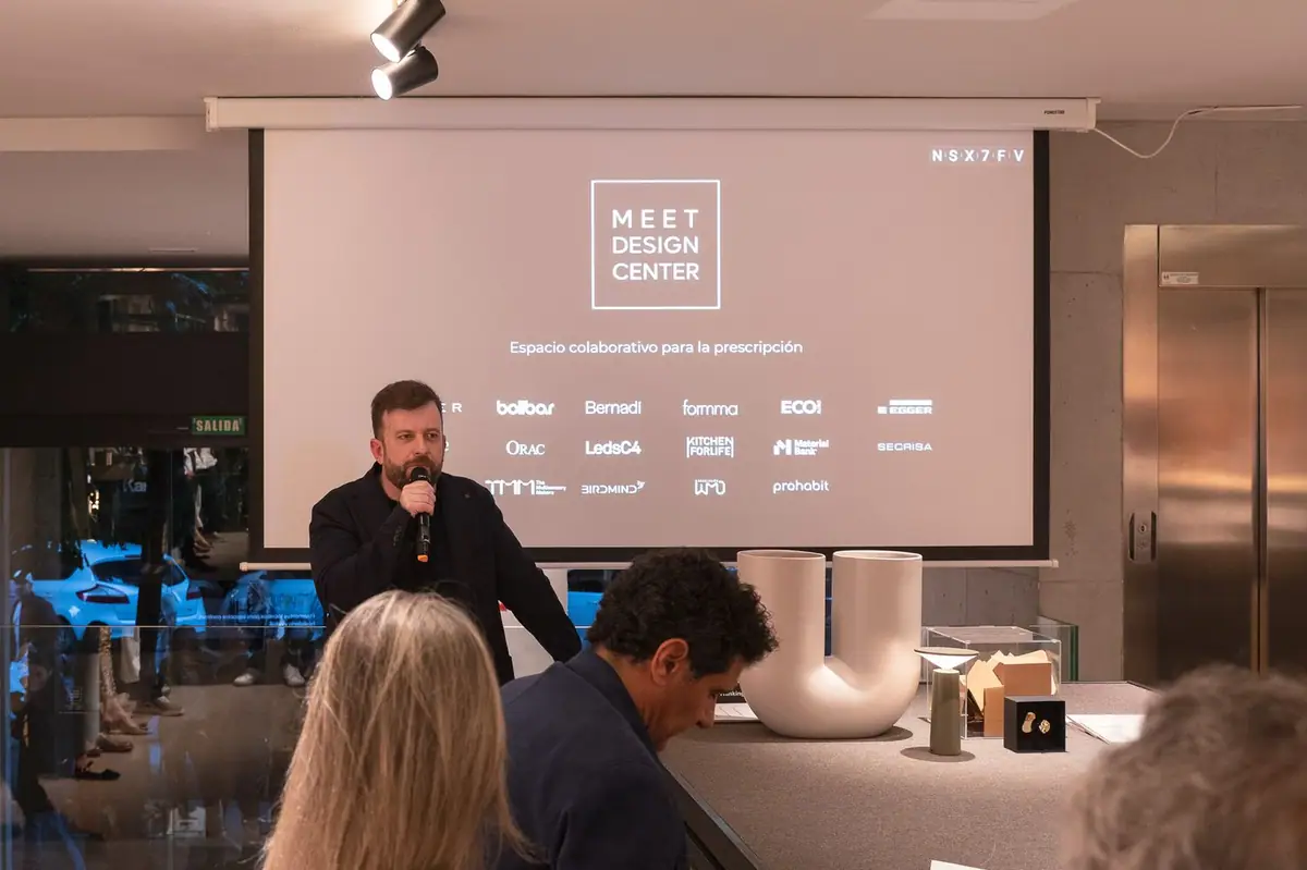 Ponente con micrófono ante una pantalla con el logotipo del Meet Design Center y las marcas participantes