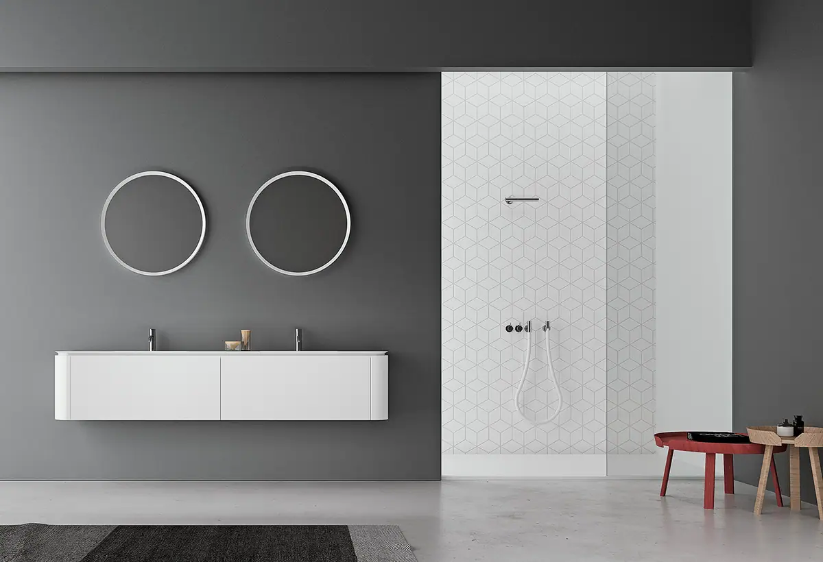 Mueble suspendido blanco con doble lavabo, dos espejos redondos de marco blanco y ducha revestida de baldosa geométrica