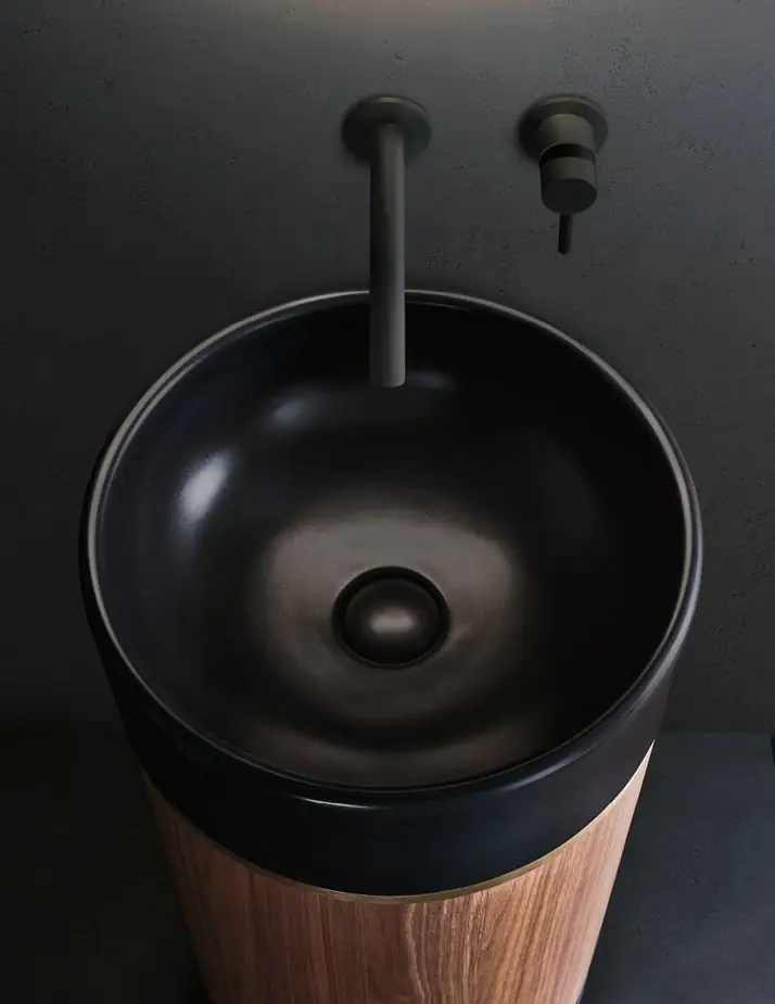Vista cenital de un lavabo de cerámica negra mate sobre un cilindro de madera de nogal, con grifería mural negra.