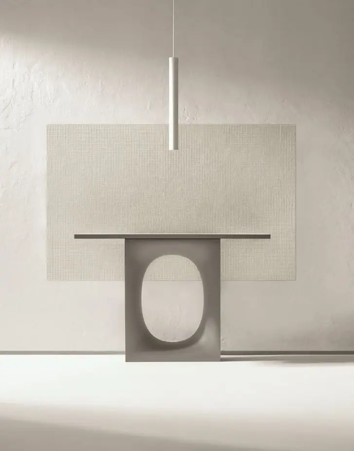 Paño de mosaico Matter Uren en tono claro sobre una pared texturizada, detrás de una consola gris con un hueco ovalado y bajo una luz de suspensión cilíndrica.