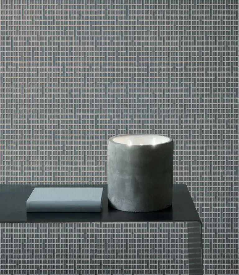 Pared y frente de un mueble revestidos con Matter Uren en un tono gris azulado, con una vela y un libro sobre la encimera.