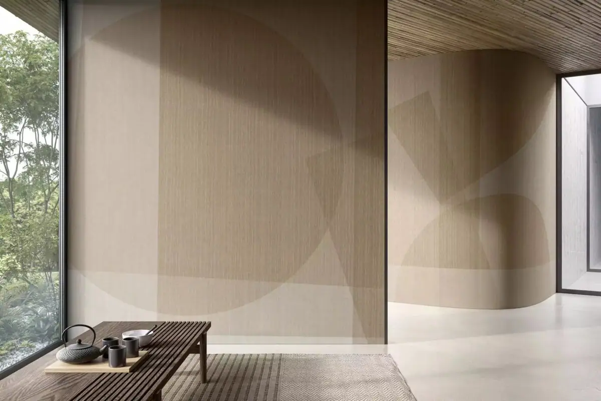 Estancia con una pared recta y otra curva revestidas con círculos y planos geométricos superpuestos en tonos arena