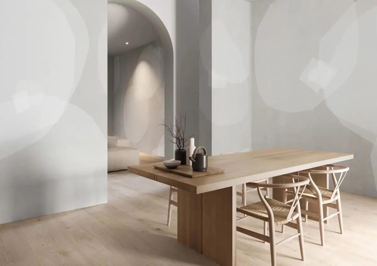 Comedor con mesa de madera ante paredes blancas con grandes formas circulares translúcidas en gris