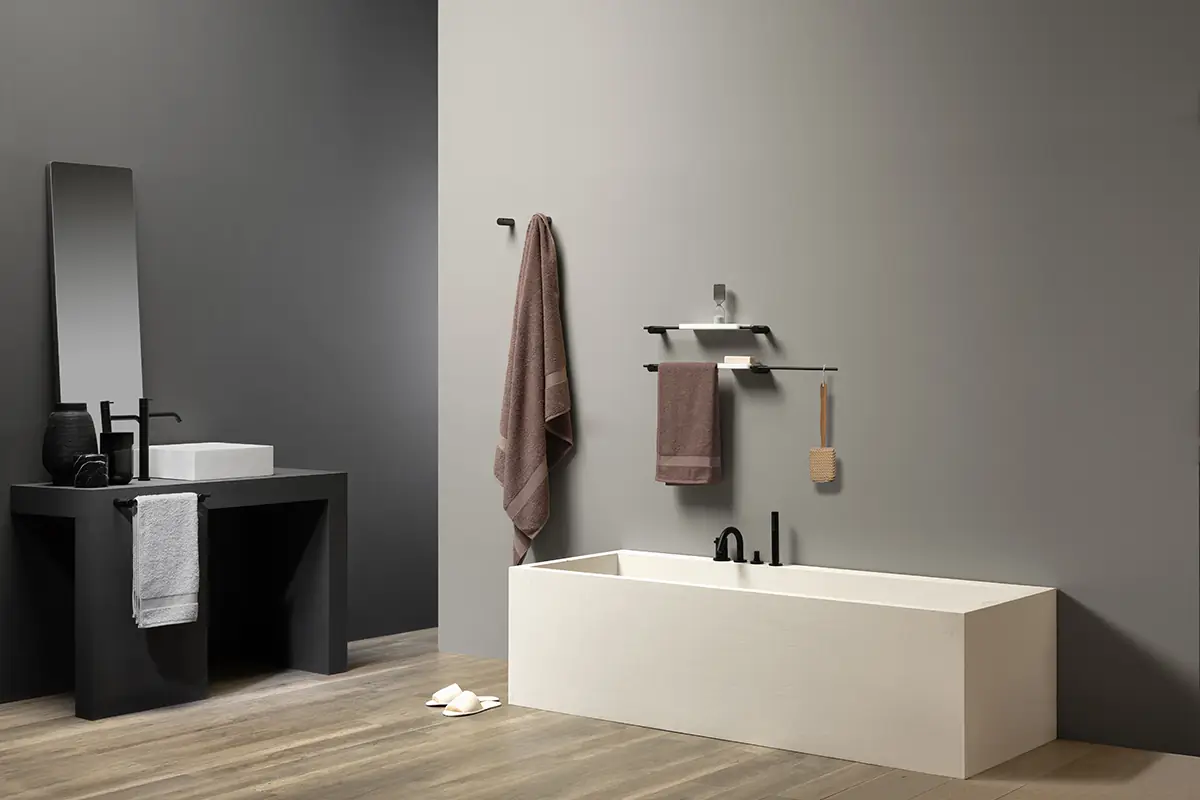 Baño con bañera exenta blanca y accesorios negros en la pared: colgador con toalla, estantes y toallero de varilla