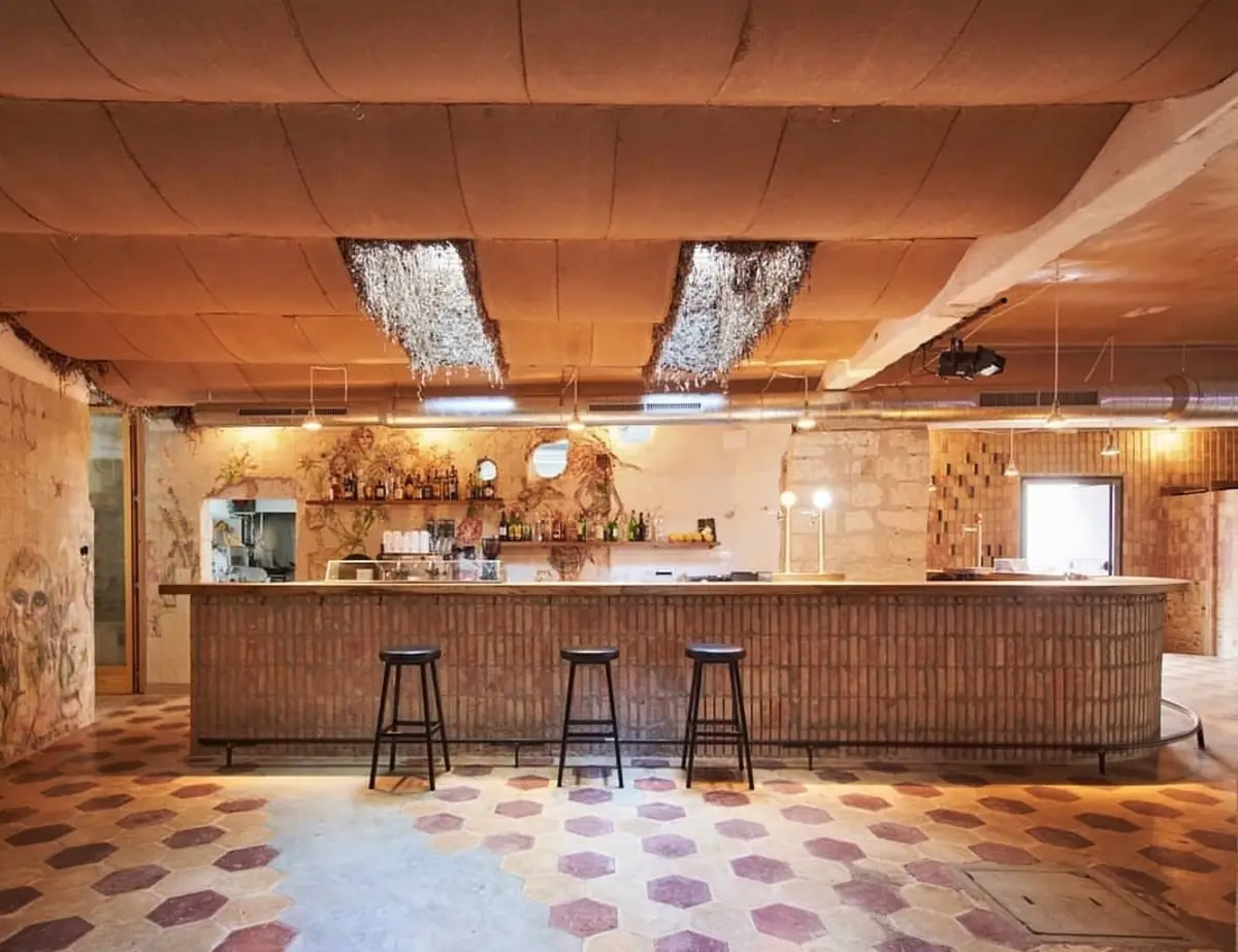 Sala con barra de ladrillo, taburetes y techo ondulado de placas de arcilla de tono terroso