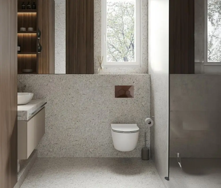 Baño con revestimiento pétreo moteado, inodoro suspendido y pulsador VORONOI marrón bajo una ventana