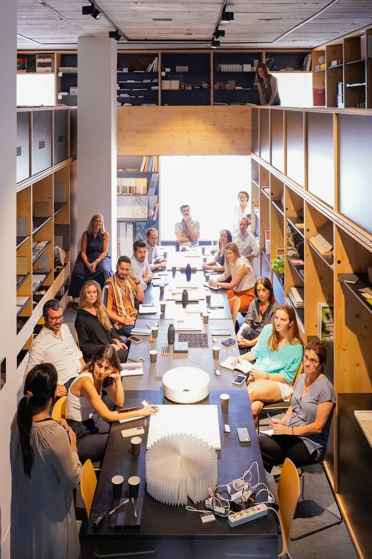 Vista vertical de la sala de la Materioteca de Matter Barcelona con los asistentes del workshop sentados alrededor de la mesa y estanterías de muestras a ambos lados.