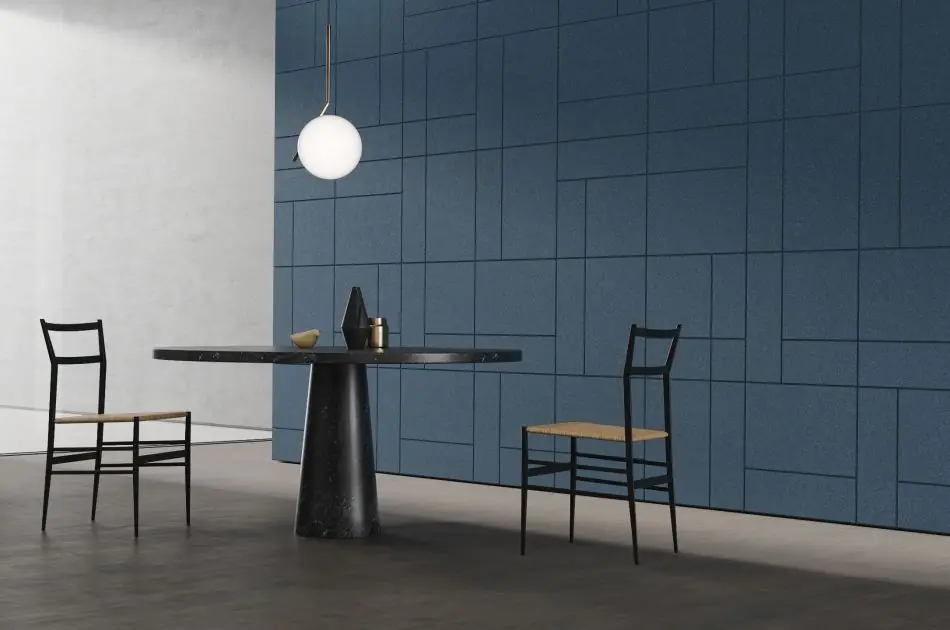 La misma composición de mesa y sillas ante una pared de placas de corcho Modular en azul