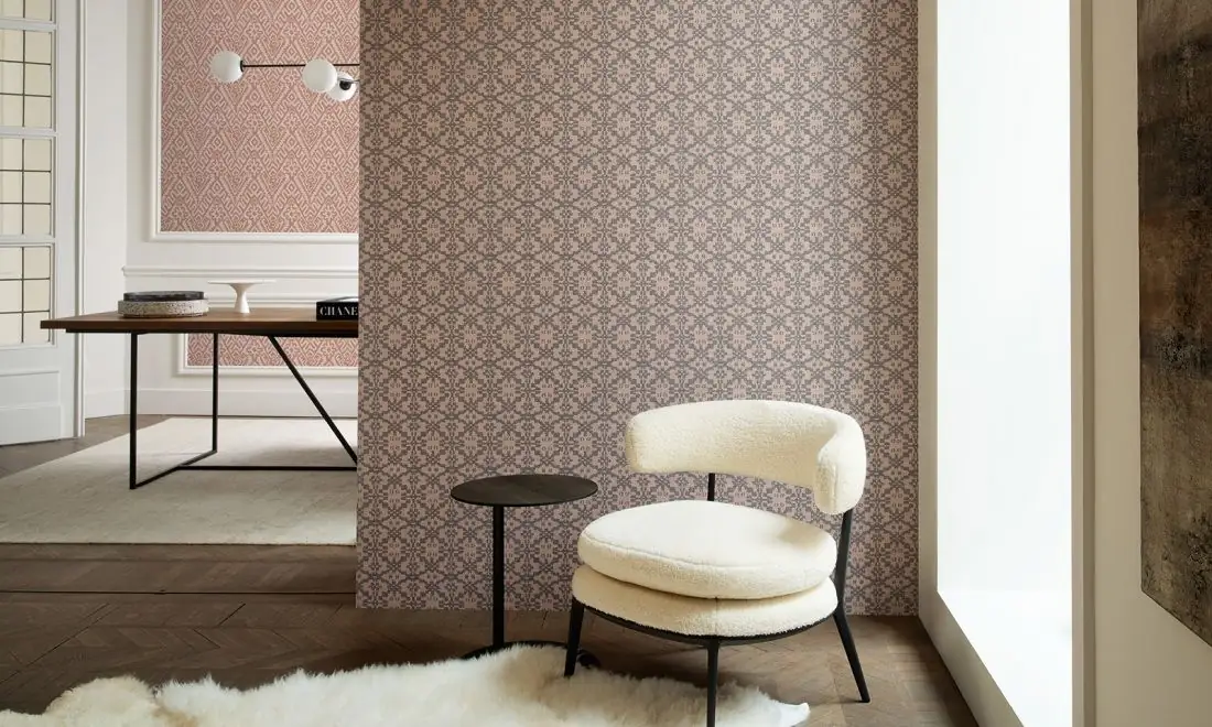 Estancia con un tabique revestido de papel pintado de pequeños motivos geométricos en rosa y gris y una butaca blanca