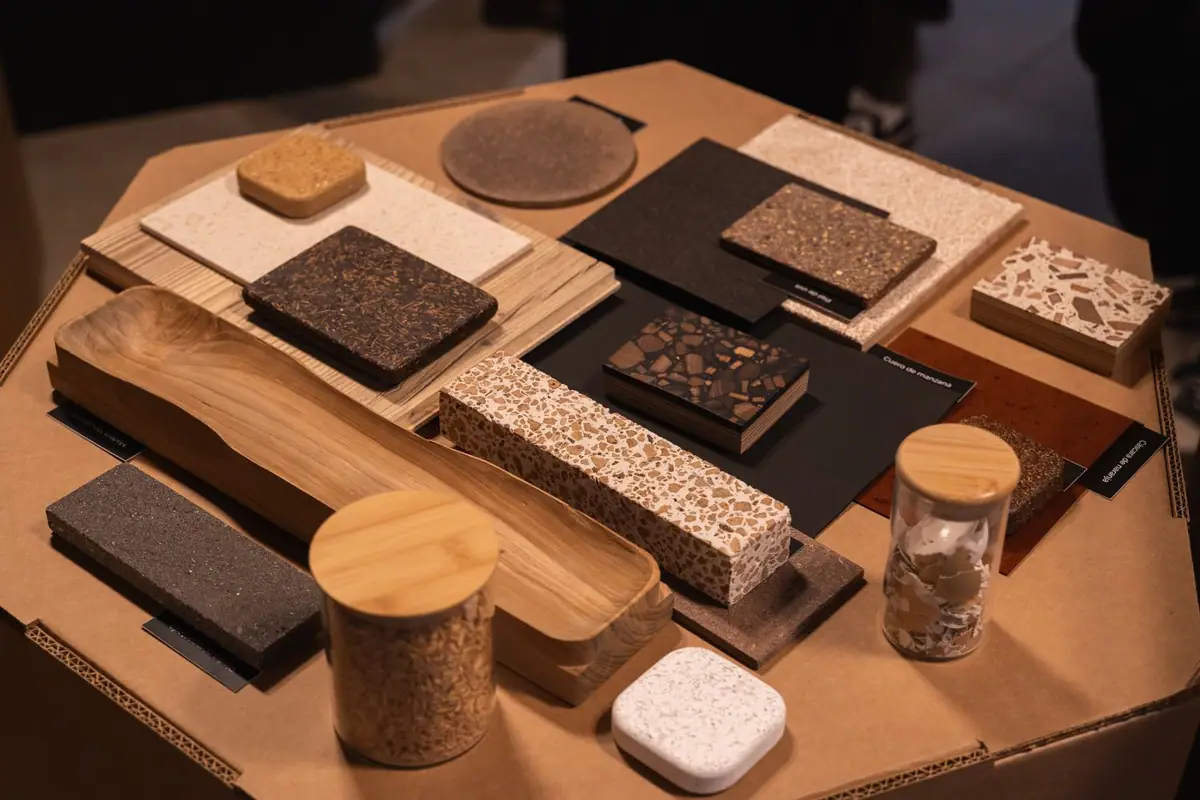 Mesa de cartón con muestras de terrazo, aglomerados de fibras, tableros de madera y tarros con residuos orgánicos
