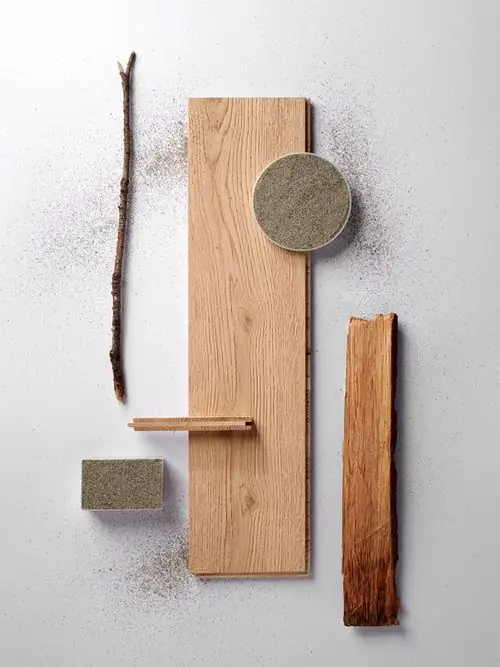 Tabla de roble claro sobre fondo blanco, con un disco de piedra gris, corteza y una rama